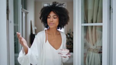 Kıvırcık kadın penceredeki yağmura dokunuyor. Portre genç Afrikalı bayan yağmurlu havanın keyfini çıkarıyor. Evdeki kameraya bakıyor. Hafta sonu sabah elinde kahve fincanı tutan romantik bir kız. İpek bornoz modeli yalnız dinleniyor. 