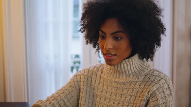 デスクワークスペースでノートパソコンを監視する無料モデル かわいい髪の懐疑的な女性の仕事のノートパソコンのソーシャルネットワークの閉鎖でチャット 一人で仕事の戦略を探すアフリカ系アメリカ人の穏やかな女性 — ストック動画