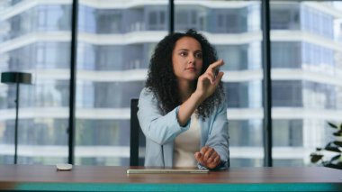 Kadın yönetici, fütüristik ofiste iş yapmak için arttırılmış realite yazılım arayüzü kullanıyor. Latin Amerikalı esmer kız görünmez dijital ekrana dokunuyor ve metaevren üzerinde çalışıyor.. 