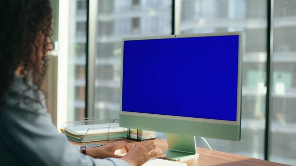 Unknown director typing mockup device keyboard closeup. Focused professional woman reading blue screen at panoramic windows office. Latin manager browsing internet working alone. Chroma key concept