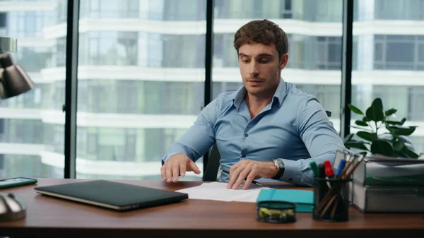 Exhausted young businessman taking work documents reading unsatisfied information close up. Young tired man business owner analysing financial report feeling unsuccessful. Company crisis concept.