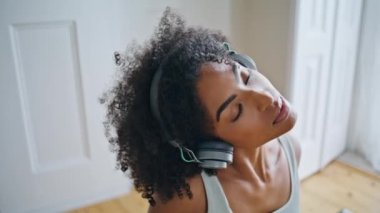 Kapalı gözlü kız sabahları boynunu ısıtıyor. Rahat bir Afrikalı kadın evde egzersiz yapıyor. Koyu tenli, sakin bir kadın, beyaz bir dairede yoga yapıyor. Refah kavramı 
