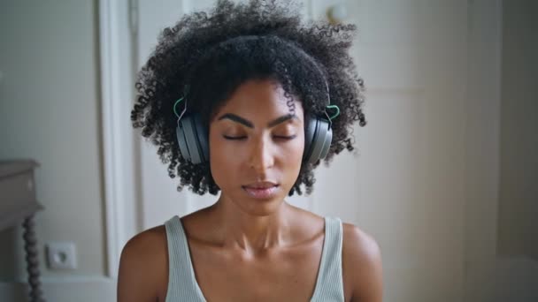 ヨガの女性は 空気を吸い込む白い部屋を閉じます 目を閉じて深呼吸瞑想をする穏やかな若い女性 ヘッドフォンでヨガプラナヤマ運動を練習アフリカの静かなモデル セレニティコンセプト — ストック動画