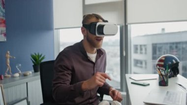 Fütürist flama düz yakın planda metaevren simülasyonu oynuyor. Gözlüklü adam artırılmış gerçekliği tek başına keşfediyor. Hippi dairesinde el kol hareketi yapan sarışın bir adam. Heyecanlı siber oyuncu