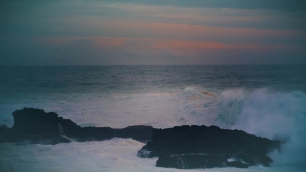 暗いスカイラインで海岸の岩を打つ嵐の海 息をのむような夕景 早朝にスプラッシュビーチの石を破る強力な泡波 スローモーションで美しい曇りの海岸風景 — ストック動画