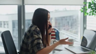 Hareketli kız cep telefonunu uzaktan çekimde açıklıyor. Panoramik pencere işyerindeki telefon görüşmesi sinirlerimi bozdu. Kızgın proje yöneticisi tek başına akıllı telefon sohbetinde sorunları çözüyor.
