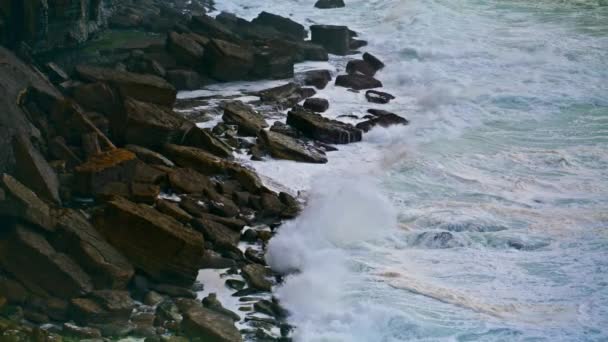 在暴风雨的日子里 充满泡沫的海洋冲刷着岩石海岸线 强大的海浪冲破了海滩 造成了缓慢的爆炸 美丽而壮观的大海冲击着狂暴的海滨石头 风景海景自然 — 图库视频影像
