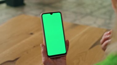 Kapalı mekanda Chromakey telefon gösteren yakın plan kadın. Tanımlanamayan iş kadını iş yerindeki yeşil ekran akıllı telefondan konuşuyor. Sanal sohbet şablonunda yer alan el hareketleriyle yönetici