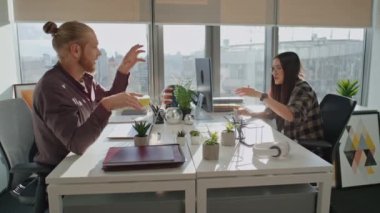 Küçük bir çalışma odasında beyin fırtınası yapan oyuncu meslektaşlar. Mutlu iş arkadaşları sunumu tartışıyor. Kadın ve erkeğin birlikte çalışması. Serbest çalışanlar keyifli konuşuyorlar. Ortaklık kavramı