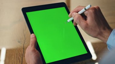 Kromakey sekme ekranında sanatçı el çizimi stili. Yeşil ekranlı tablet bilgisayarda elektrikli kalem kullanan yaratıcı iş adamı parmakları. Ofis masasında çalışan tanınmayan tasarımcı.