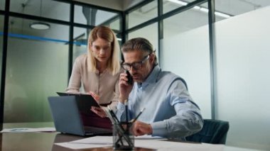 Ofiste birlikte çalışan iki çalışan yakın plan. İş adamları toplantı odasında laptopun beyin fırtınası yapıyor. Telefonu arayan adam ekranda görünüyor. Güvenilir meslektaşlar sunumu tartışıyor. Şirket işi 