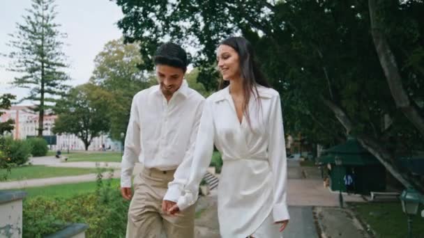 一对浪漫的夫妇在户外走楼梯 英俊的黑发绅士在绿色的天性中与微笑的女朋友交谈 西班牙裔快乐的夫妇享受结婚周年纪念日在夏日植物园散步 — 图库视频影像