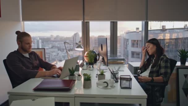 스타트업들이 사무실에서 일하고 아시아 파노라마 창문턱에서 마사지하는 남자는 노트북 테이블에서 — 비디오