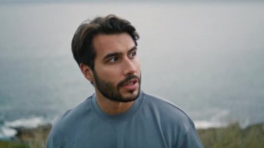 Sakin sakallı adam kasvetli deniz kıyısında tek başına yürüyor. Bulutlu doğa sahillerinde gezinen yakışıklı genç adam. Gevşemiş çekici turist, kumsalda bulutlu bir hafta sonunun keyfini çıkarıyor. Tatil gezisi konsepti.