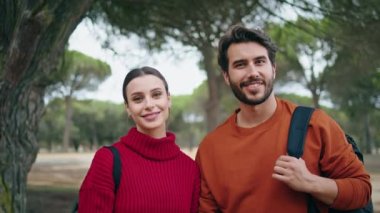 Güzel bir sonbahar ormanında sırt çantalarıyla gülümseyen iki pozitif yürüyüşçü. Neşeli genç bir çiftin portresi. Mutluluk duygusu. Tatili doğada geçirmek. Aile çiftleri birlikte rahatlar.