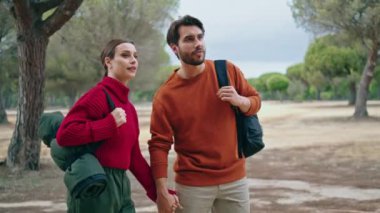 Sırt çantasıyla doğa yürüyüşüne çıkan gülümseyen romantik çift. Güzel bir sonbahar ormanında yürüyen mutlu bir aile. Genç turistler güneşli park manzarasının tadını çıkarıyorlar. İki gezgin birlikte geziniyor.