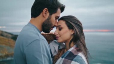 Akşam sahillerinde aşık genç çift öpüşüyor. Yaklaş. Deniz kıyısındaki kasvetli bulutlu günde sarılan mutlu, rahat bir çift. Balayını doğada geçiren iki insanı sevmek. İlişki kavramı.