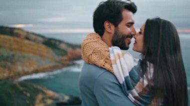 Deniz kıyısındaki bulutlu akşamda romantik mutlu çift yaklaşıyor. Gülümseyen neşeli çift, gri sakin okyanus manzarasında sarılıyorlar. Kaygısız kadın erkek, aile hafta sonunun tadını çıkarır. Tatil kavramı.