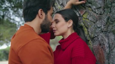 Birbirini seven romantik çiftin portresi orman ağacının yanında durmuş birbirine sevgiyle bakıyor. Güzel, genç bir çift doğada birlikte vakit geçiriyorlar. Yakın çekim. Sevimli aile yakınlık hissi rahatlatıcı..