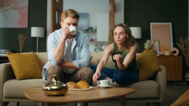 平静的一对聊天沙发在家里喝着早晨的浓缩咖啡 松懈的男朋友女友冷冰冰的沙发一起讨论日常事务 休息的女人在客厅里喝杯酒 — 图库视频影像