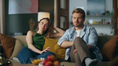 Sıkılmış eşler evde film izlerken ilgisiz hissediyorlar. Gülümseyen kadın koltuğa bakıp gülmeye başladı. Oturma odasında oturan aptal TV şovuna bakan aşk çifti. Çevrim içi eğlence