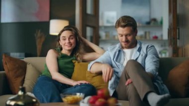 Rahatlamış ortaklar akşam televizyon izlerken kanepede dinleniyorlar. Filmi seçen kanalları çeviren gülümseyen adam. Kocasıyla el hareketi yapan olumlu bir kadın. Genç aile birlikte oturma odasında vakit geçiriyor.
