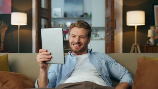 兴奋的家伙在室内实现了平板电脑变焦 满意的男人读着标签屏幕说哇在家里关门 感情用事的嬉皮士键入数码平板设备 独自做出令人惊讶的表情 — 图库视频影像