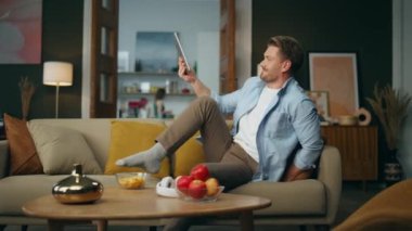 Akşamları evde tablet bırakan kaygısız bir beyefendi. İnternette gezinen bilgisayarları izleyen pozitif bir adam. Gülümseyen adam dijital cihaz kullanarak boş zaman harcıyor. Teknoloji ve insan yaşam tarzı kavramı