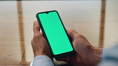 Ofiste adamın elleri kromakey cep telefonunu yakın çekimde tutuyor. Tanımlanamayan yönetici yeşil ekran cihazında haber alışverişini kontrol ediyor. Bilinmeyen CEO akıllı kontrol uygulaması kullanıyor. İşçi sanal çağrı konuşuyor 