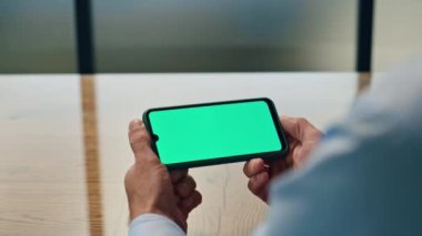 İşadamı elleri iş yerinde kromakey cihazını yakından izliyor. Elinde yatay yeşil ekran cep telefonu tutan tanınmayan bir adam. Bilinmeyen CEO akıllı telefondan çalışıyor. Patron telefonda bekliyor.