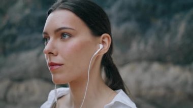 Sandy Hill 'in önünde modern kulaklıklarla müzik dinleyen rüya gibi güzel bir kadının portresi. Çekici, rahat kız kulaklıkla şarkı söylemekten hoşlanıyor. Sahilde duran romantik genç bayan.