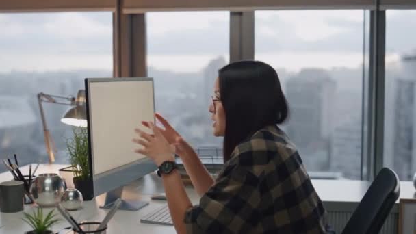 在橱窗办公室的特写镜头前给女人解释的姿势情绪设计师在电脑桌上与同事交谈 积极开发人员在晚上城市视图工作场所进行沟通 嬉皮士女孩聊天 — 图库视频影像