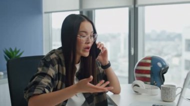 Kızgın iş kadını ofis telefonuyla tartışıyor. Panoramik pencere evinde el hareketleriyle konuşan gergin kız. Uzaktaki iş yerinde mobil sohbeti sonlandıran üzgün yönetici