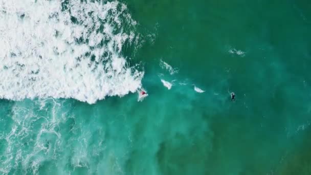 ターコイズブルーの海のプールでのトップビューのサーファースイミング美しい夏の週末 熱帯のビーチに圧延泡立つ嵐の波 空中ショット未知の人々が青い海の水の遅い動きにサーフボード — ストック動画