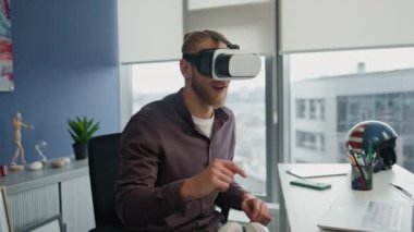 Fütürist flama düz yakın planda metaevren simülasyonu oynuyor. Gözlüklü adam artırılmış gerçekliği tek başına keşfediyor. Hippi dairesinde el kol hareketi yapan sarışın bir adam. Heyecanlı siber oyuncu