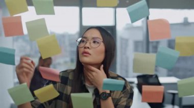 Düşünceli serbest çalışan, duvardaki çıkartmayı yakından inceliyor. Genç iş kadını, şeffaf notlar üzerine görevler yazıyor. Ciddi kız büyük vitrinlerdeki iş yerinde yaratıcı fikirler üretiyor. 