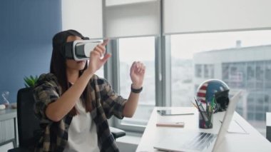 Şehir manzaralı dairede VR teknolojilerini inceleyen kulaklıklı kadın. Blue Wall Ofisi 'nde geliştirilmiş gerçeklik üzerinde çalışan yaratıcı oyun tasarımcısı. Odaklanmış serbest çalışan tek başına 3D programı test ediyor. Yüksek teknoloji konsepti 