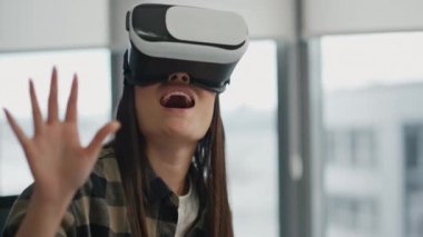 Uzaktan kumanda odasında sanal gerçekliği izleyen mutlu kadın. Dijital gözlüklerle kollara dokunan heyecanlı kız simülasyonu. Gülümseyen acemi yalnız yaratıcı iş yerinde siber ortamda eğleniyor.