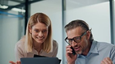 Aşırı neşeli iş adamları modern ofiste seviniyor. Heyecanlı meslektaşlar, beş başarıyı birlikte yakından izliyorlar. Sakallı işadamı evet diyerek telefonu arıyor. İş ortakları proje kazanıyor