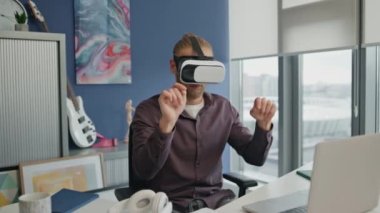 Modern işyerindeki hava paneline dokunan VR programcısı. Şehir manzaralı ofiste geliştirilmiş gerçeklik projesine odaklanmış. Deneyimli bir adam interaktif arayüzü evde kullanıyor