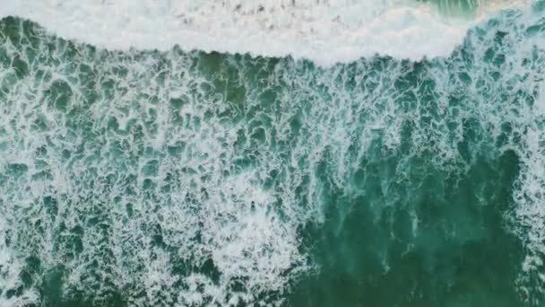 美しい泡立ち波がビーチの空中ビューで転がります 美しい海の景色ターコイズブルーの海の水を洗う海岸超スローモーション 白い泡で穏やかな海の波のしぶき 旅行の自然概念 — ストック動画