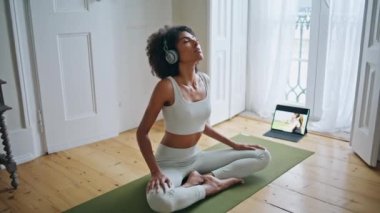 Nilüfer çiçeği halının üzerinde otururken poz verir. Afro-Amerikalı sakin bayan evde meditasyon yapıyor. Genç kıvırcık sporcu kadın yoga yapıyor. Tablet spor kanalı seyrediyor. Düşünceli, zayıf kız yalnız başına dinleniyor.