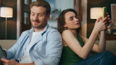 Sevgi çifti, rahat ev zoom 'unda aletler kullanıyor. Kapalı mekanda erkek arkadaşına cep telefonu gösteren olumlu bir kadın. Kanepeye gülümseyen adam tepki veriyor. Yakın plan mutlu ortaklar evde birlikte dinleniyorlar.