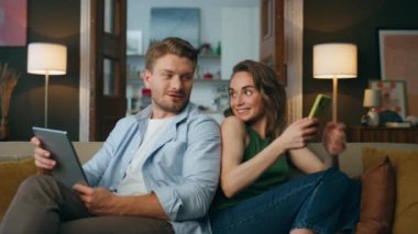 Konuşan çiftler kanepeyi yakınlaştırıyor. Kanepeye yakın otururken telefonu kullanan gülümseyen kadın. Evde tablet bilgisayar ve kitap okuyan olumlu bir adam var. İnternet bağımlısı aile hafta sonu konsepti