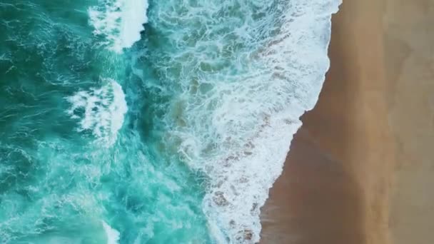 超スローモーションで美しい空のビーチを洗う青い海の波を表示します 空中の息をのむような海の景色砂の海岸に圧延泡立つ水 嵐のターコイズブルーの海が海岸線に飛び散る — ストック動画
