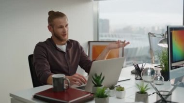Dinlenme tasarımcısı laptopçuda konuşuyor. Yakın çekim. Bilgisayar masasında gülümseyen kadın meslektaşı. Şehir manzaralı ofiste iki kişi konuşuyor. Rahatlamış girişimciler akşam işyerinde mola veriyorlar.