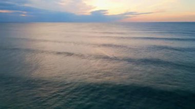 Yaz akşamından sonra güzel, bulutlu, sonsuz okyanus ufku. Hava manzarası güneş batarken deniz yüzeyini sersemletiyor. Karanlık, derin su dalgaları güneş ışığını yansıtıyor. Doğa sükuneti kavramı.