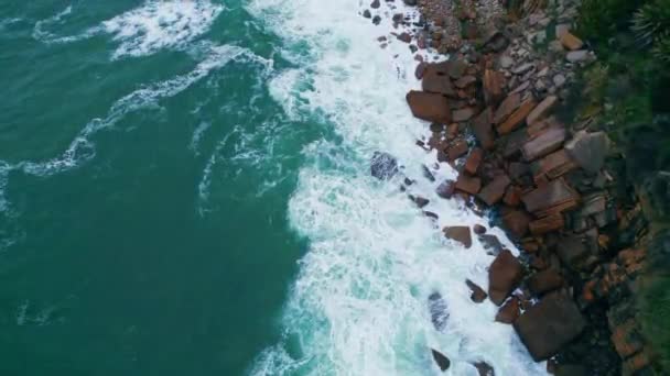 白い泡で海岸の石を壊す嵐の海を一望できます 空中の泡立ちの海の水が岩だらけの海岸でゆっくりと動きに墜落する ダークブルーの波が海岸の崖を洗う 海洋性の概念 — ストック動画