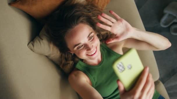 Chica Feliz Saludando Mano Hablando Teléfono Inteligente Casa Sofá Vista — Vídeos de Stock