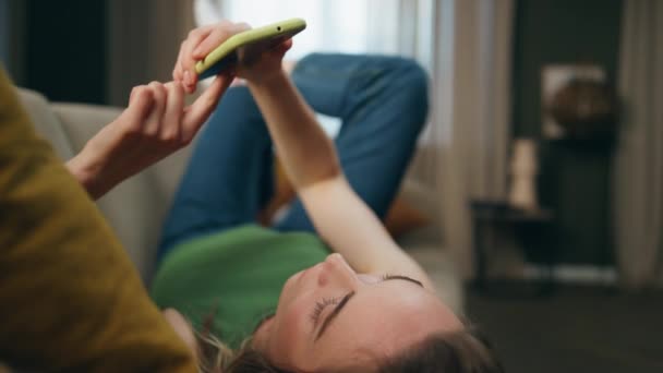 Gadis Santai Meletakkan Sofa Menonton Smartphone Dekat Rumah Headphone Wanita — Stok Video